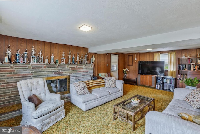 living room featuring carpet flooring, a textured ceiling, a fireplace, and wood walls