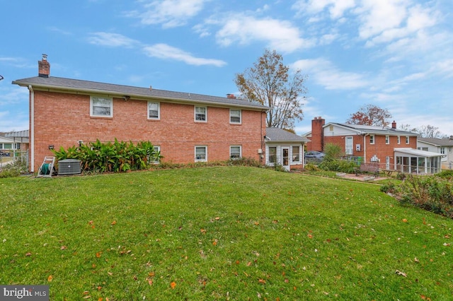 rear view of property featuring a yard and central air condition unit