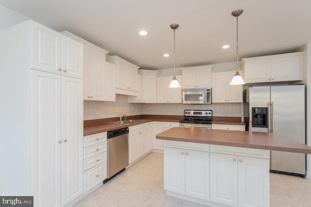 kitchen with white cabinets, pendant lighting, a center island, and stainless steel appliances