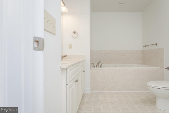 bathroom featuring tile patterned floors, vanity, toilet, and tiled bath