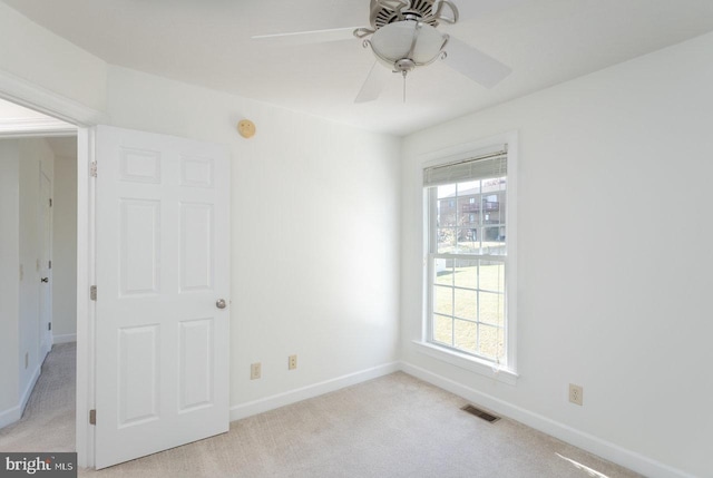 carpeted spare room featuring ceiling fan and a wealth of natural light