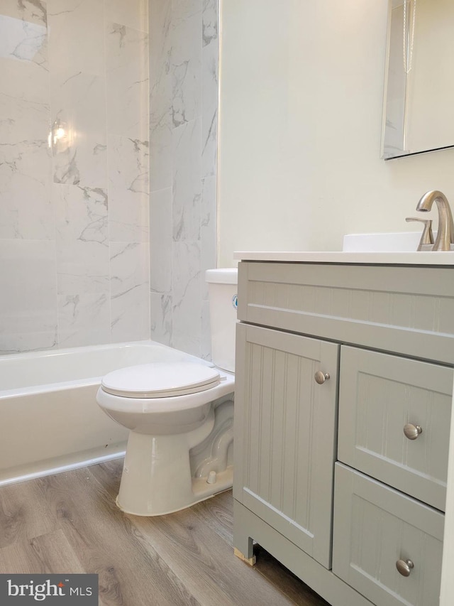 full bathroom with tiled shower / bath, vanity, wood-type flooring, and toilet