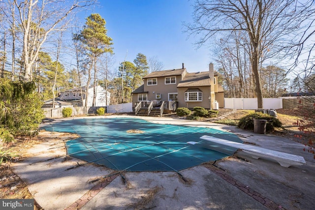 view of pool with a wooden deck, a diving board, and a patio