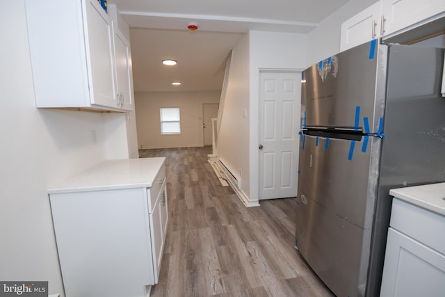 kitchen featuring white cabinets, stainless steel fridge, light hardwood / wood-style floors, and a baseboard radiator