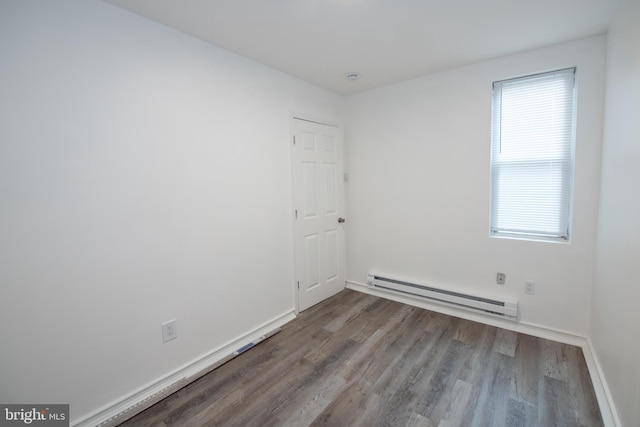 spare room featuring wood-type flooring and a baseboard heating unit