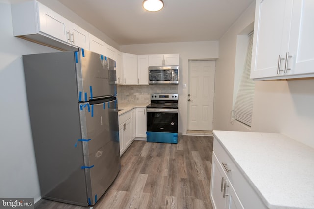 kitchen featuring white cabinets, decorative backsplash, light wood-type flooring, and stainless steel appliances