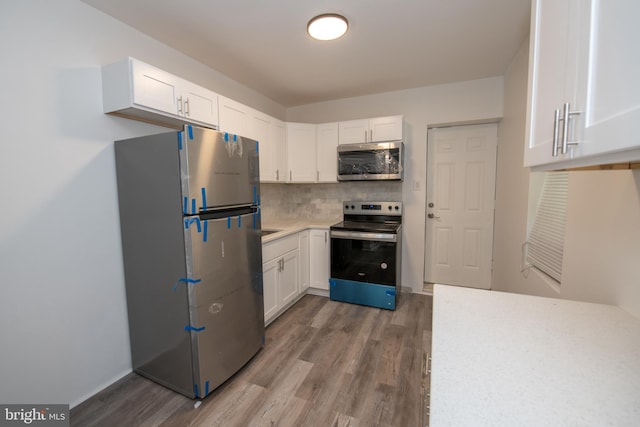 kitchen with white cabinets, backsplash, stainless steel appliances, and hardwood / wood-style flooring