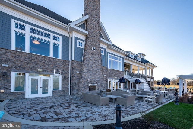 back of property with a patio area, an outdoor living space, and french doors