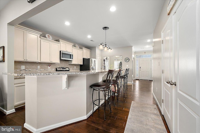 kitchen featuring dark hardwood / wood-style flooring, a center island with sink, and appliances with stainless steel finishes