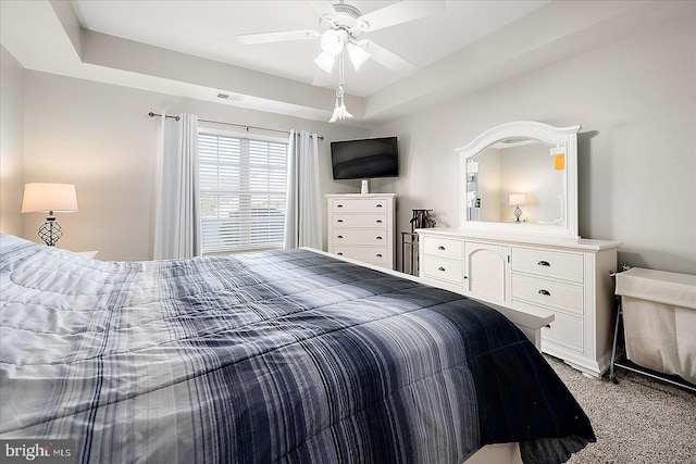 bedroom featuring carpet, a raised ceiling, and ceiling fan