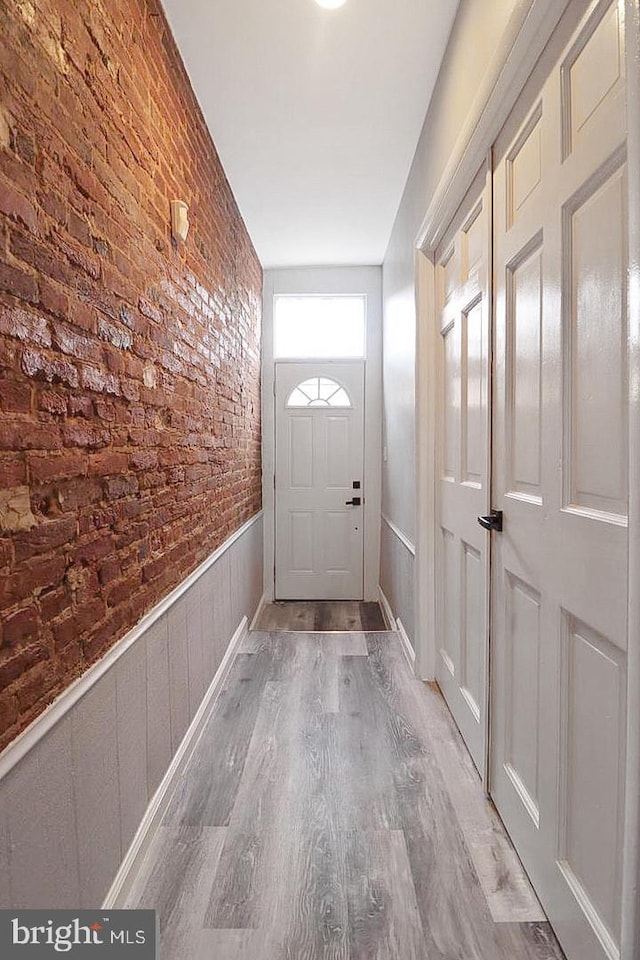 doorway featuring light hardwood / wood-style floors and brick wall