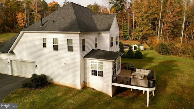 back of property with a lawn, a garage, and a deck