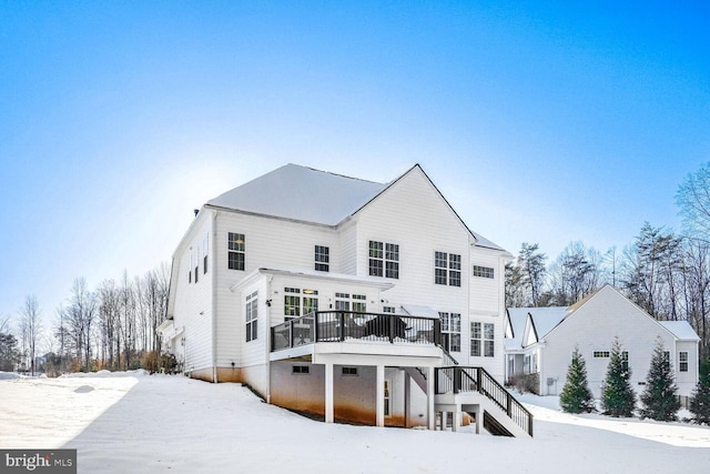 snow covered back of property featuring a deck