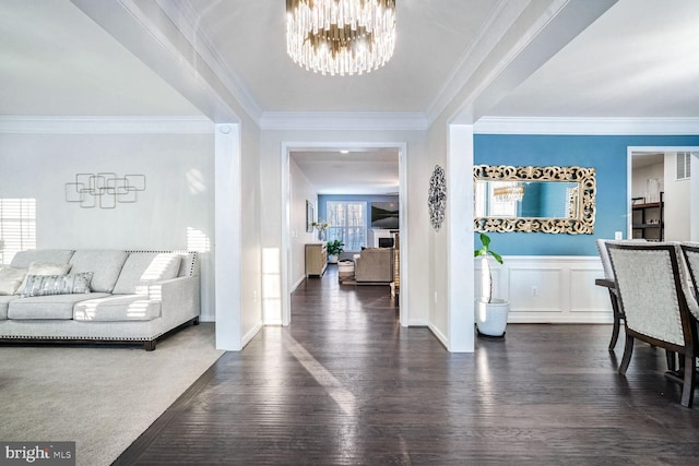 entryway with dark hardwood / wood-style flooring, ornamental molding, and a notable chandelier