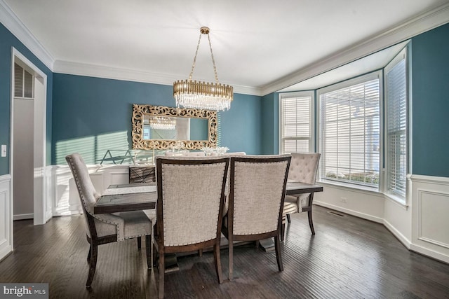 dining space featuring dark hardwood / wood-style floors, ornamental molding, and an inviting chandelier