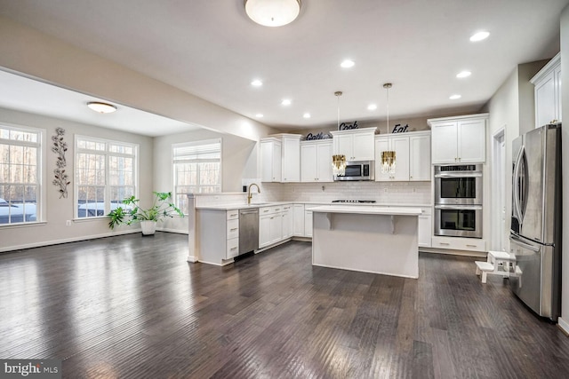 kitchen with white cabinets, decorative light fixtures, kitchen peninsula, and stainless steel appliances