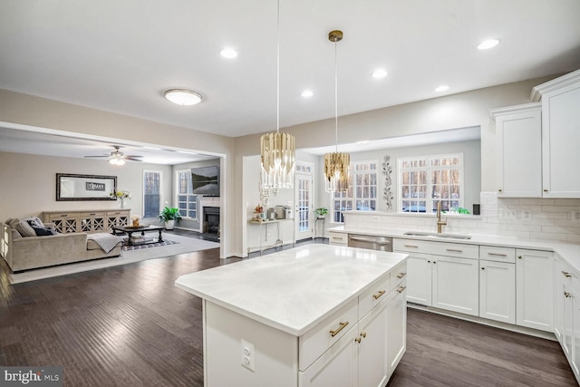 kitchen with white cabinetry, sink, stainless steel dishwasher, pendant lighting, and a kitchen island