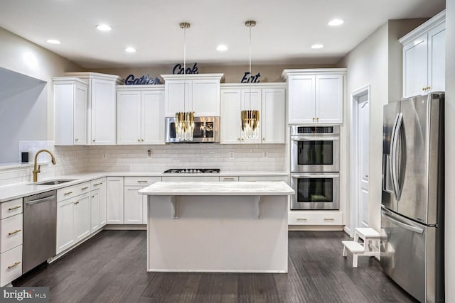 kitchen with stainless steel appliances, dark wood-type flooring, sink, white cabinetry, and hanging light fixtures