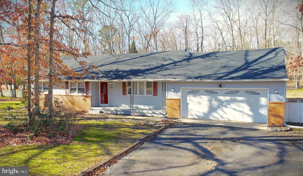 ranch-style home featuring covered porch and a garage