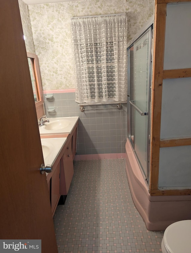 full bathroom featuring vanity, bath / shower combo with glass door, tile patterned flooring, toilet, and tile walls