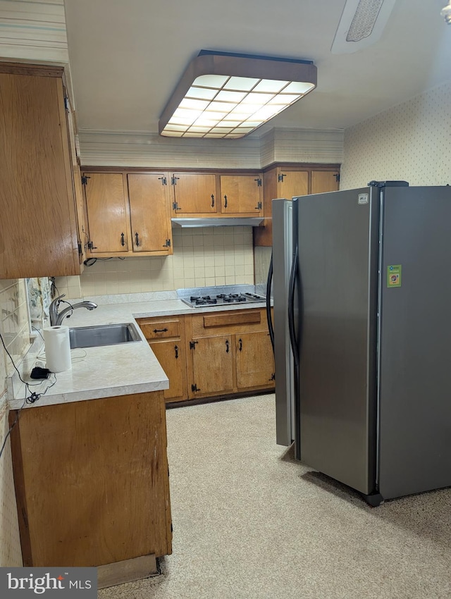 kitchen featuring decorative backsplash, sink, stainless steel refrigerator, and gas cooktop