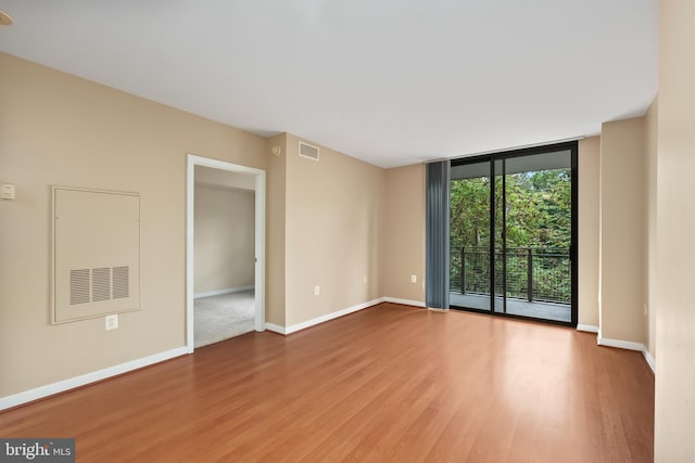 unfurnished room with hardwood / wood-style floors and expansive windows