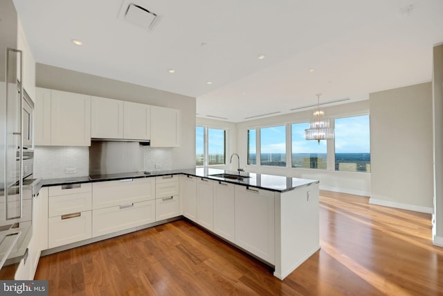 kitchen featuring pendant lighting, light hardwood / wood-style floors, white cabinetry, and sink