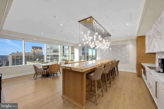 50 S 16th St Unit 5102, Philadelphia, PA 19102 - kitchen featuring light wood-style flooring, white cabinetry, a kitchen breakfast bar, light stone countertops, and recessed lighting