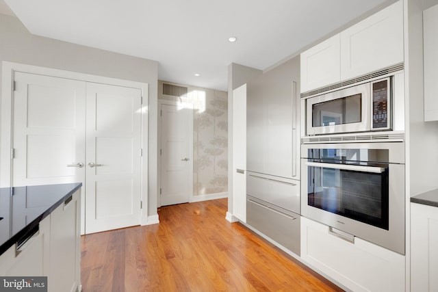50 S 16th St Unit 5102, Philadelphia, PA 19102 - kitchen with wall oven, stainless steel microwave, dark countertops, light wood finished floors, and white cabinetry
