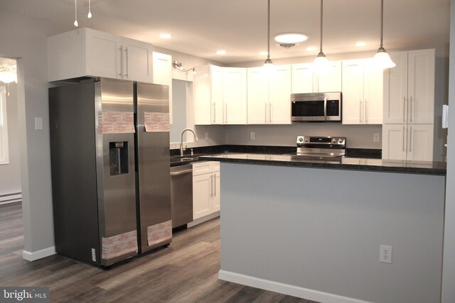 kitchen with white cabinets, sink, appliances with stainless steel finishes, decorative light fixtures, and dark hardwood / wood-style flooring