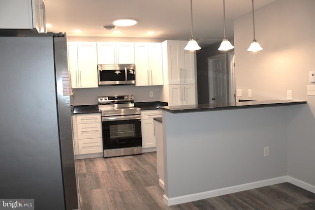 kitchen with white cabinets, appliances with stainless steel finishes, kitchen peninsula, and dark wood-type flooring