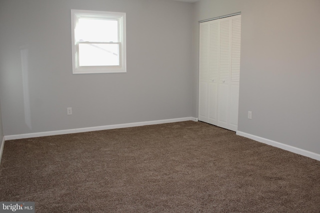 unfurnished bedroom featuring a closet and dark colored carpet