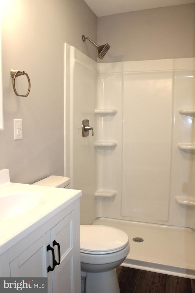 bathroom featuring a shower, vanity, hardwood / wood-style flooring, and toilet