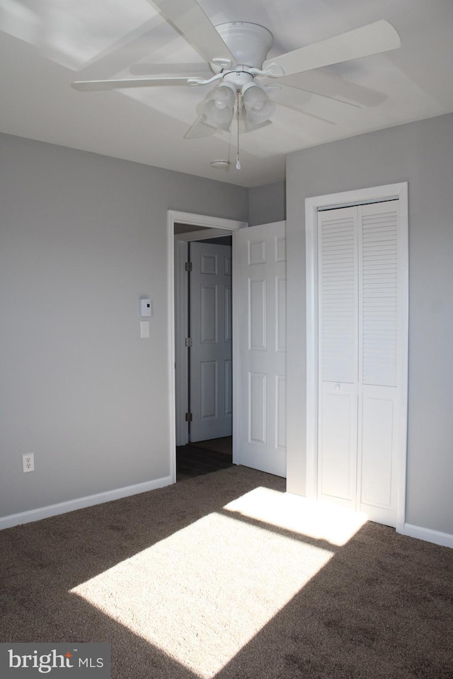 unfurnished bedroom with ceiling fan, a closet, and dark carpet