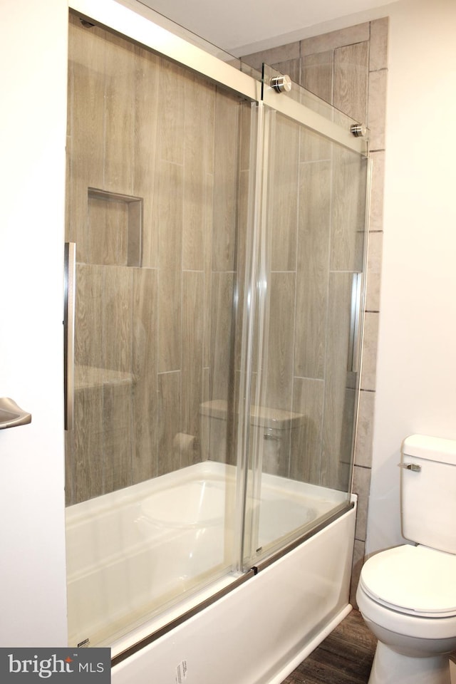 bathroom featuring bath / shower combo with glass door and toilet