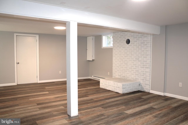 basement featuring dark wood-type flooring and a baseboard heating unit