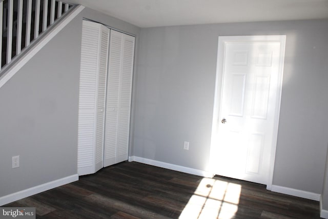 unfurnished bedroom with dark wood-type flooring and a closet