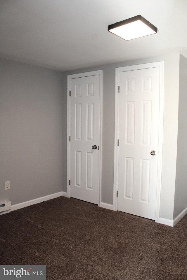 unfurnished bedroom with a baseboard radiator and dark colored carpet