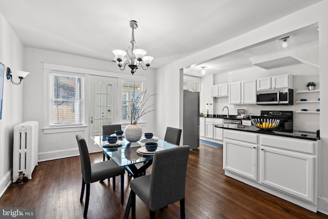 dining room with dark hardwood / wood-style flooring, radiator heating unit, a chandelier, and sink