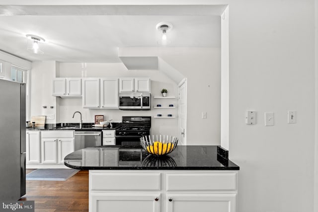 kitchen featuring dark hardwood / wood-style flooring, stainless steel appliances, sink, dark stone countertops, and white cabinets