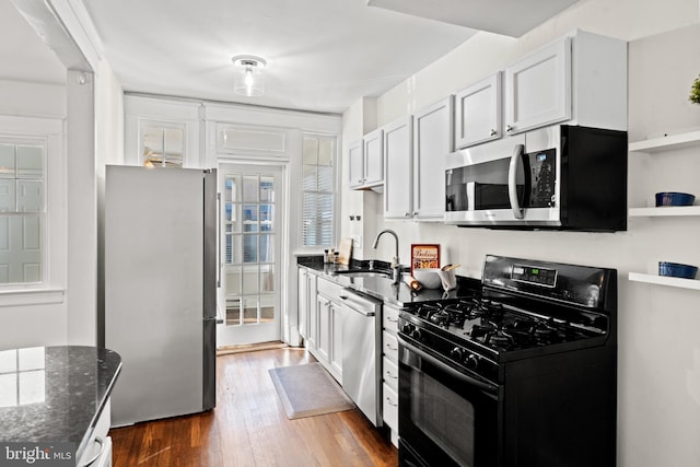 kitchen featuring white cabinets, dark hardwood / wood-style flooring, stainless steel appliances, and dark stone counters