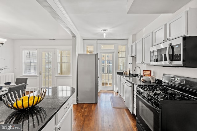 kitchen with dark stone counters, white cabinetry, and stainless steel appliances