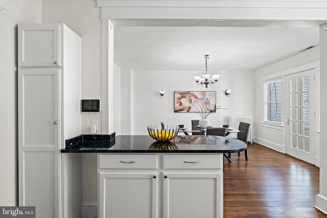 kitchen with dark wood-type flooring, decorative light fixtures, a notable chandelier, dark stone countertops, and white cabinetry