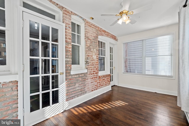 empty room with ceiling fan, dark wood-type flooring, and brick wall