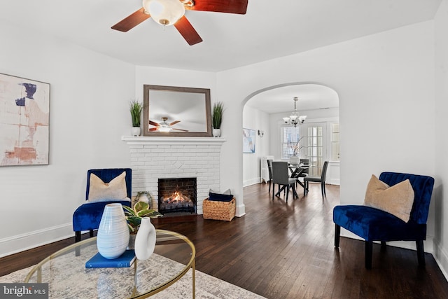 living room featuring a fireplace, ceiling fan with notable chandelier, dark hardwood / wood-style floors, and radiator