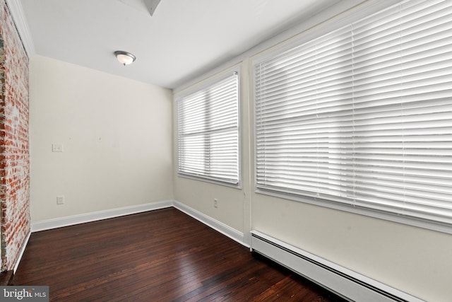 empty room featuring baseboard heating and dark wood-type flooring