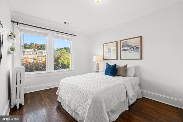 bedroom with radiator heating unit, dark hardwood / wood-style flooring, and ornamental molding