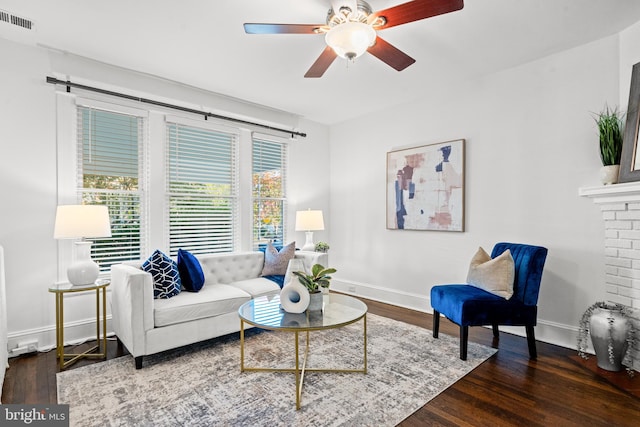 living room featuring ceiling fan, dark hardwood / wood-style floors, and a brick fireplace