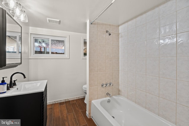 full bathroom with toilet, vanity, tiled shower / bath combo, and hardwood / wood-style flooring