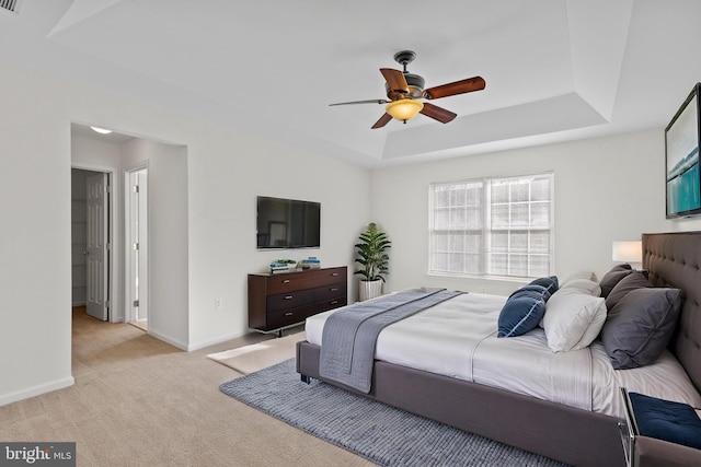 carpeted bedroom featuring a raised ceiling and ceiling fan